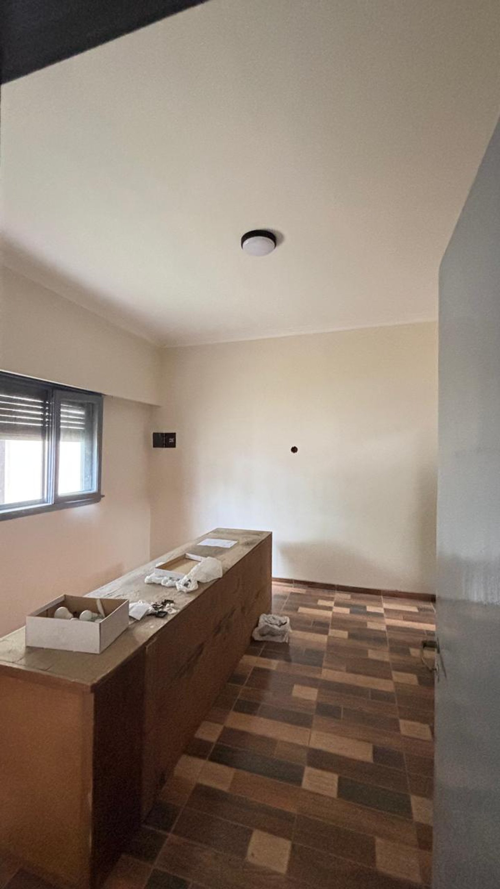 Ambiente com ilha longa de madeira e piso de cerâmica quadriculado — projeto REFORMA C520, por Estudio Llobet, em Melchor Romero